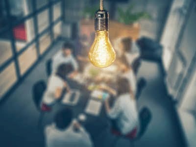 A business meeting under the glow of a lightbulb.